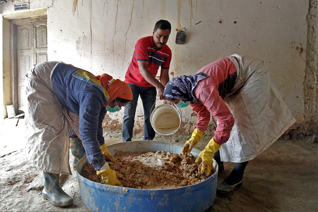 Workers prepare a concoction to bait the giant African land snails inside a coffee estate. Co-ordinated efforts of farmers and officials have recently helped curb the infestation. Credit: Abhishek Chinnappa/Mongabay